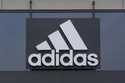A sign is displayed in front of an Adidas retail store in Paramus, N