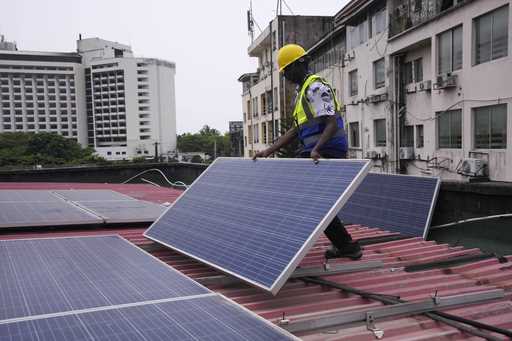 Oladapo Adekunle, an engineer with Rensource Energy, installs solar panels on a roof of a house in …