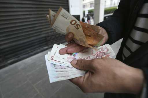 A man holds Algerian and European, top, bank notes Friday, February 9, 2024 in Algiers