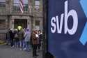 A law enforcement official, behind, stands in an entryway to a Silicon Valley Bank branch location,…