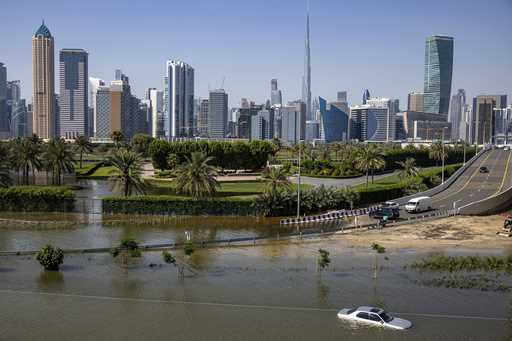 An abandoned vehicle stands in floodwater caused by heavy rain with the Burj Khalifa, the world's t…