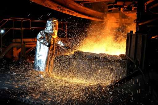 A worker in a protective suit pokes a metal rod to tap slag from a smelting furnace at PT Vale Indo…