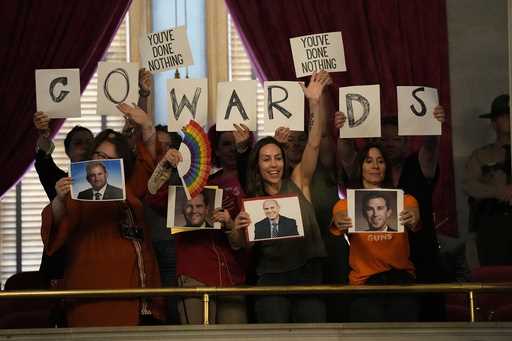 People in the gallery hold signs over the House chamber floor during a legislative session Thursday…