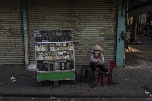 A vendor selling used remote controls for various home appliances takes a nap in Nhat Tao market, t…
