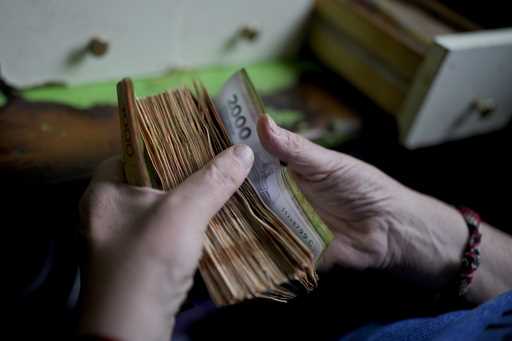 File - A worker counts money at a grocery store in Buenos Aires, Argentina, November 21, 2023
