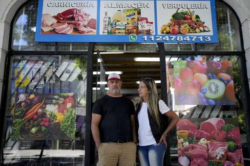 Sergio Gómez and Carla Cavallini pose for a picture outside their store, in Buenos Aires, Argentina…