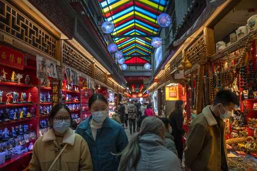 Visitors look at shops selling trinkets and souvenirs along a tourist shopping street in Beijing, F…