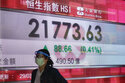 A woman walks past a bank's electronic board showing the Hong Kong share index in Hong Kong Tuesday…
