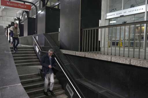 Men walk down stairs to a train station in front of the Reserve Bank of Australia in Sydney, Tuesda…
