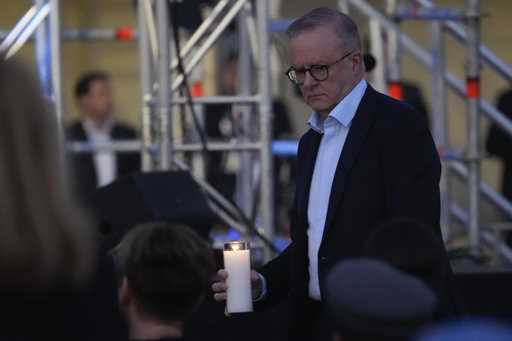 Australian Prime Minister Anthony Albanese carries a candle during a candlelight vigil at Sydney's …