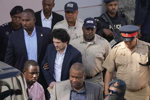 FTX founder Sam Bankman-Fried, center left, is escorted out of Magistrate Court following a hearing…