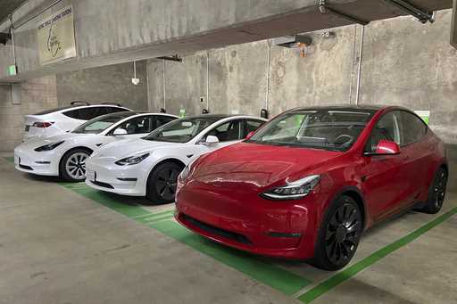 This photo provided by Edmunds shows a line of parked Tesla Model 3 and Model Y vehicles