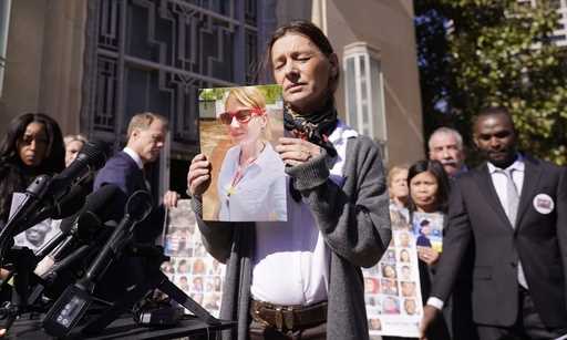 Catherine Berthet, of France, closes her eyes as she holds a photo of her deceased daughter Camille…