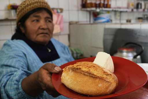 A vendor gives "pan de batalla," or battle bread, which is made with government subsidized flour, t…