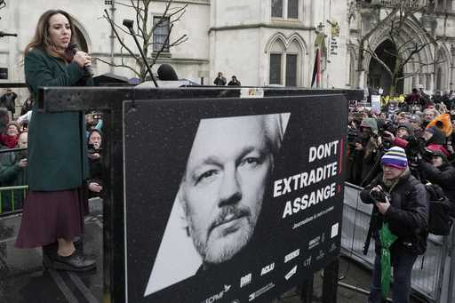 Stella Assange, wife of Julian Assange, speaks besides a poster of Julian Assange at the Royal Cour…