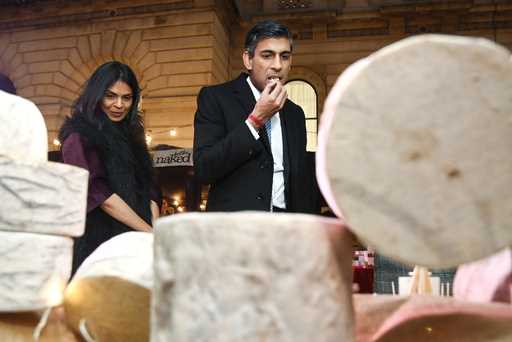 Britain's Prime Minister Rishi Sunak samples a cheese next to his wife Akshata Murty as they visit …