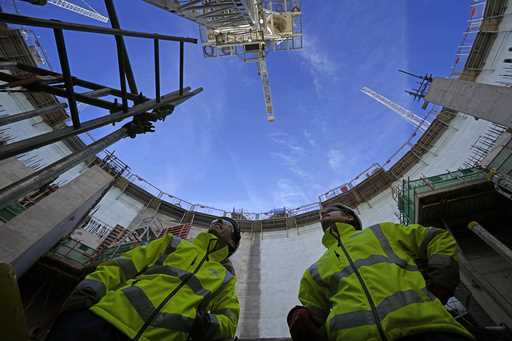 Employees look up at the construction site of Hinkley Point C nuclear power station in Somerset, En…