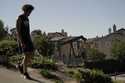 A man walks along the street as a pump jack extracts oil at a drilling site next to homes Wednesday…