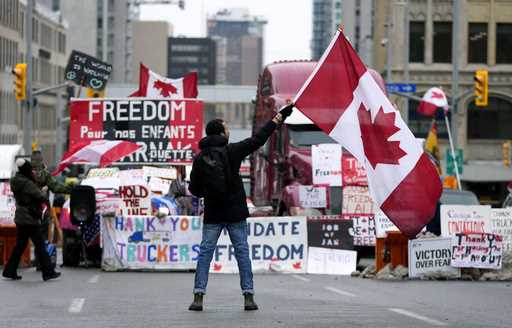 A protester waves a Canadian flag in front of parked vehicles at a protest against COVID-19 measure…