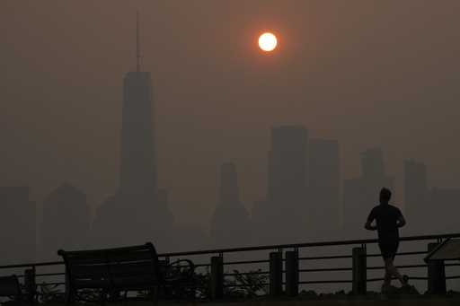 A man runs in front of the sun rising over the lower Manhattan skyline in Jersey City, N