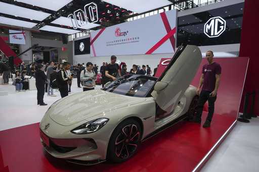 Visitors look at an MG car during the opening of China Auto Show in Beijing, China, Thursday, April…