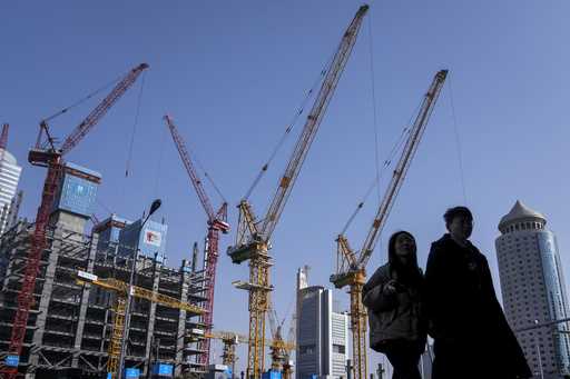 A young couple walk by a construction site near office buildings in the Central Business District i…
