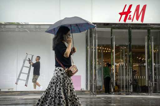 A worker carries a ladder as he works on a window display for a clothing store at a shopping mall i…