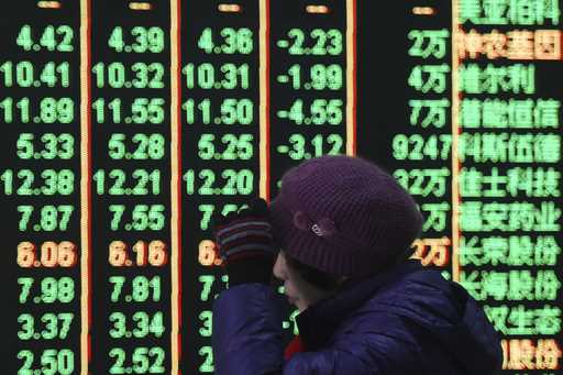 A woman reacts in front of an electronic screen displaying stock prices at a brokerage house in Han…