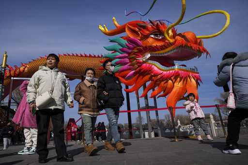 People walk by a giant dragon lantern decorated near the frozen Houhai Lake in Beijing, Thursday, F…