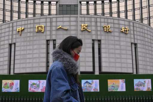 A woman walks by China's central bank, or the People's Bank of China in Beijing, Tuesday, February …