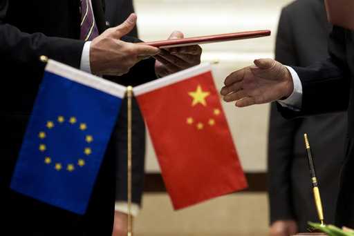 A member of European Commission, left, prepares to exchange documents with Chinese delegation at a …