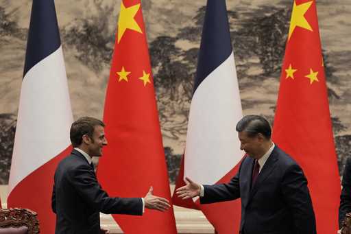 FILE- French President Emmanuel Macron, left, shakes hands with Chinese President Xi Jinping after …