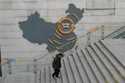 A man walks past a depiction of Evergrande properties across a China map at a partially shuttered E…