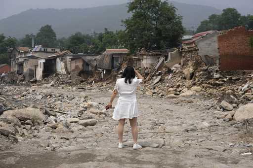 A woman reacts as she fails to find her house after flood waters devastate Nanxinfang village on th…