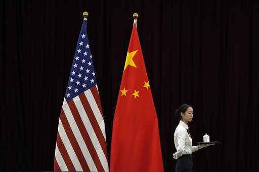A hostess walks by the national flags of the United States and China ahead of the bilateral meeting…