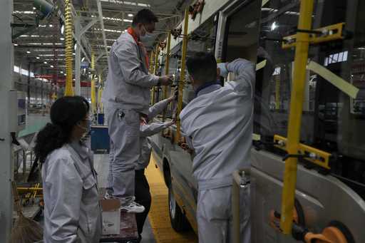 Workers install window panels on a minibus at a factory during a media organized tour in Shiyan cit…