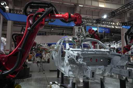 Visitors look at the robotic arms assembly a vehicle frame during the annual World Robot Conference…