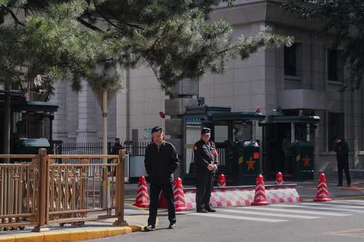 A man walks by Chinese security personnel guarding the entrance to the Jingxi Hotel where the Commu…
