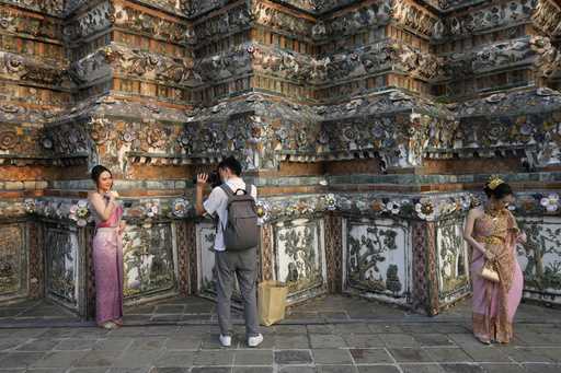 A Chinese tourist in traditional Thai dress poses for a photograp at Wat Arun or the 