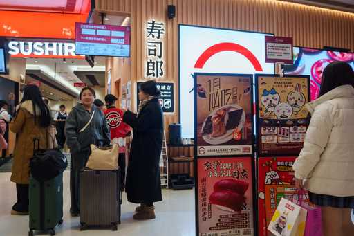 Customers wait outside a store for Sushiro, a Japan-based conveyor-belt sushi chain, in Beijing, We…