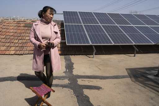 Farmer Shi Mei walks near solar panels on her rooftop in the rural outskirts of Jinan in eastern Ch…
