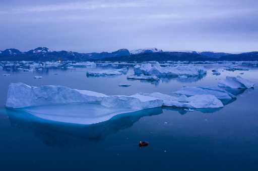 A boat navigates large icebergs near Kulusuk, in eastern Greenland, on August 15, 2019