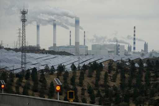 Smoking chimneys and solar panel farm are seen along a highway in a coal producing region in Yulin …