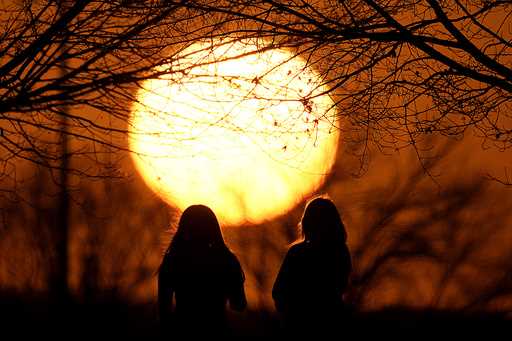 People watch the sunset at a park on an unseasonably warm day, February 25, 2024, in Kansas City, M…