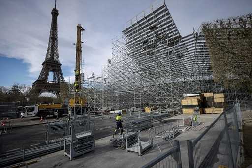 Workers build the stands for the upcoming Olympic Games on the Champ-de-Mars just beside the Eiffel…