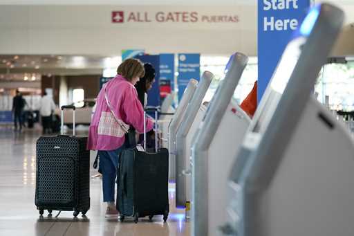 Travelers use the kiosk by the ticketing gate as they prepare for travel from Love Field airport, M…