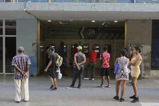 People stand in line outside a bank hoping to withdraw Cuban pesos from an ATM, in Havana, Cuba, Mo…