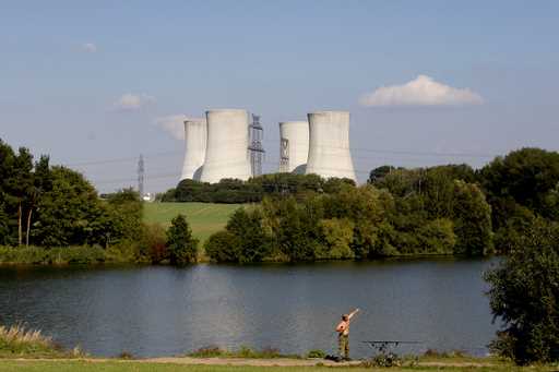 A man fishes with the towering Dukovany nuclear power plant in the background, in Dukovany, Czech R…