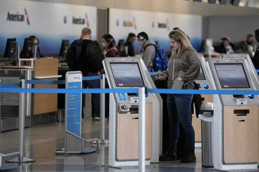 A traveler uses a kiosk to check her bags in front of the American Airlines ticketing gate at Dalla…