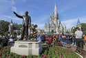 A statue of Walt Disney and Micky Mouse stands in front of the Cinderella Castle at the Magic Kingd…